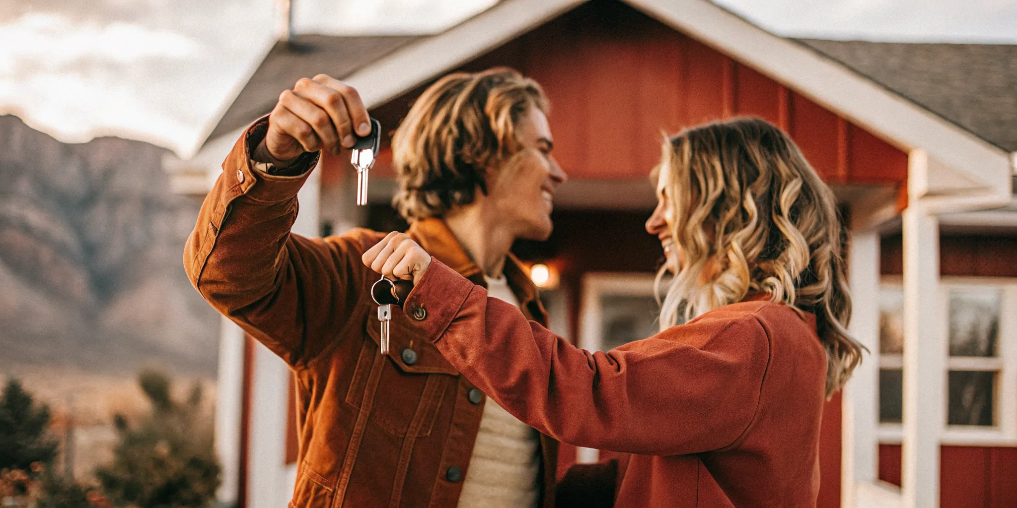 Young couple in front of their new Washington State home with mountains in the background