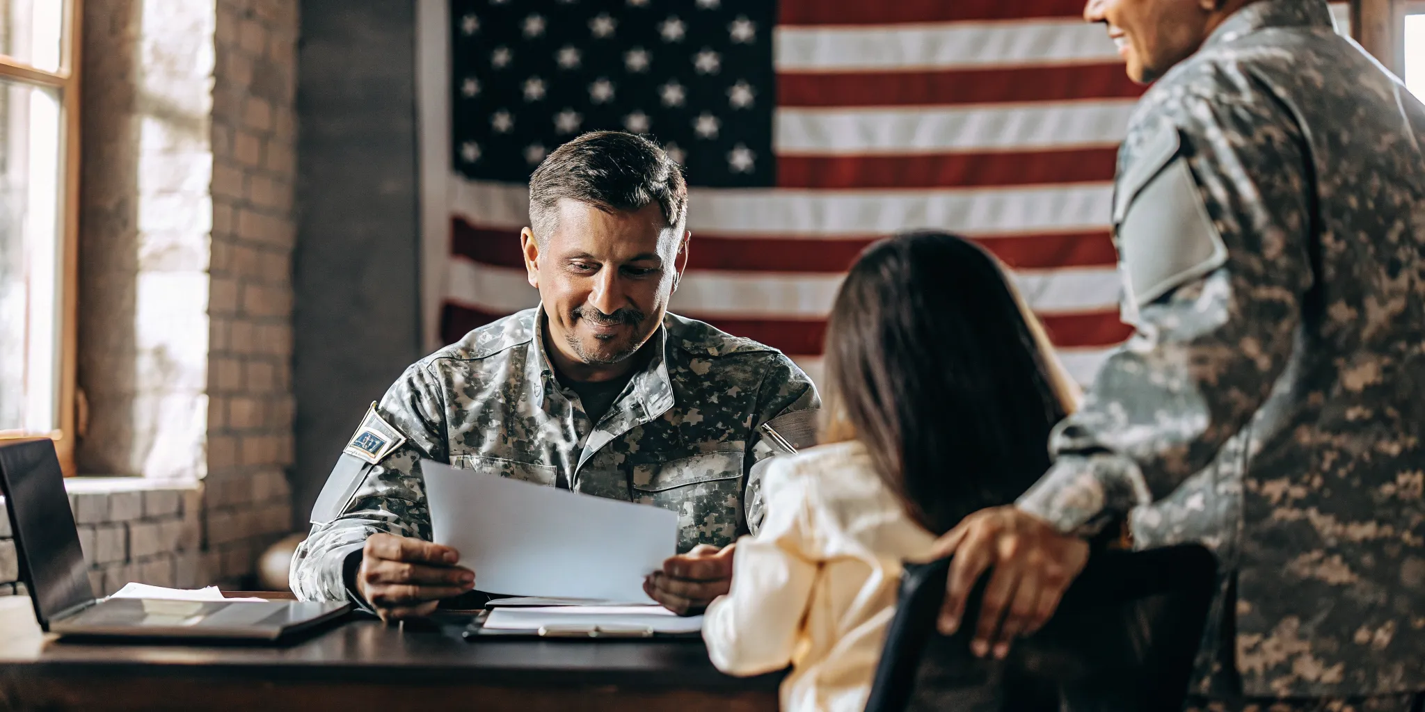 Veteran mortgage loan officer speaking with a military family in a warm professional office