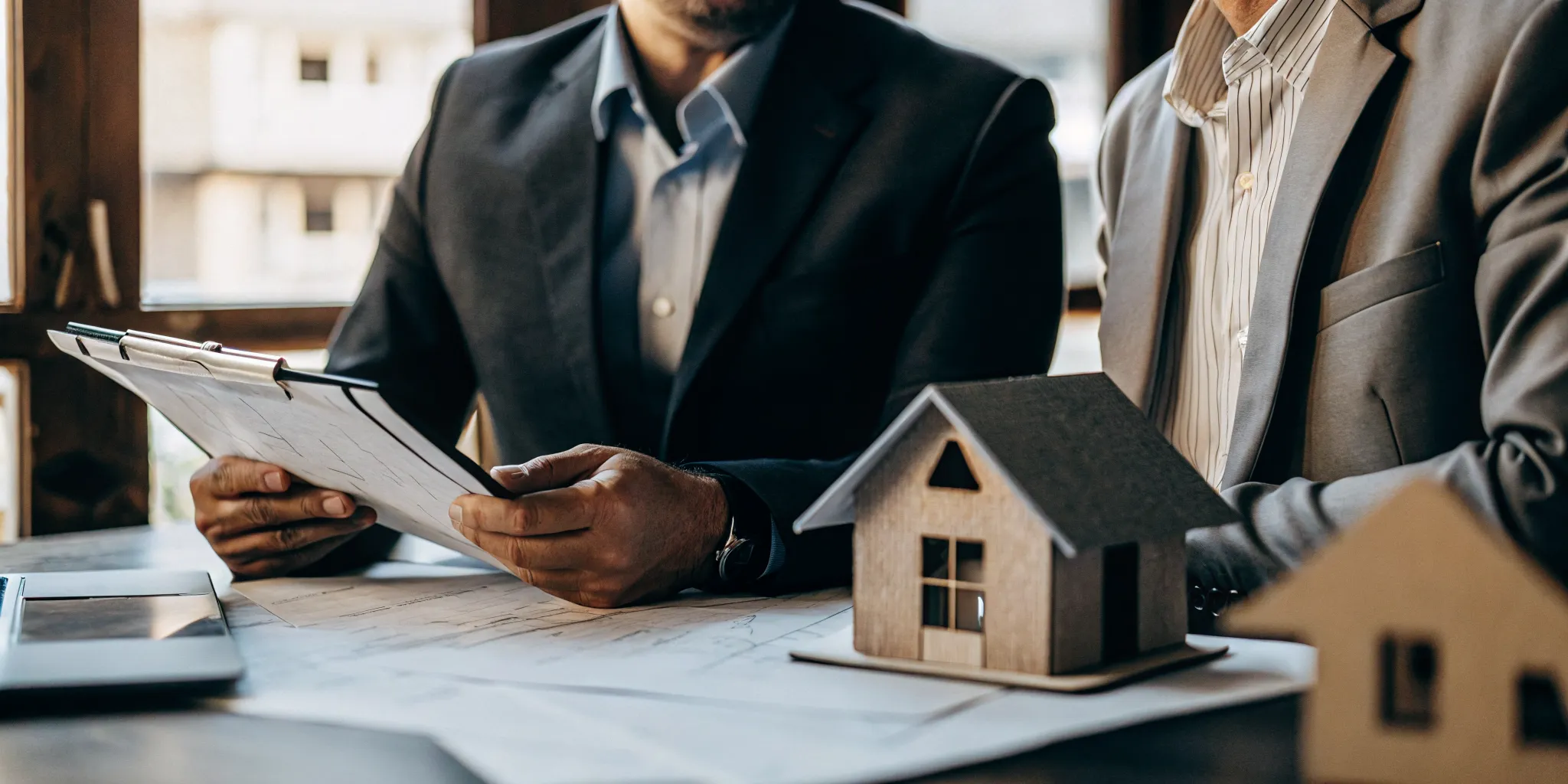 Real estate investor reviewing property documents with a mortgage advisor in a professional office setting